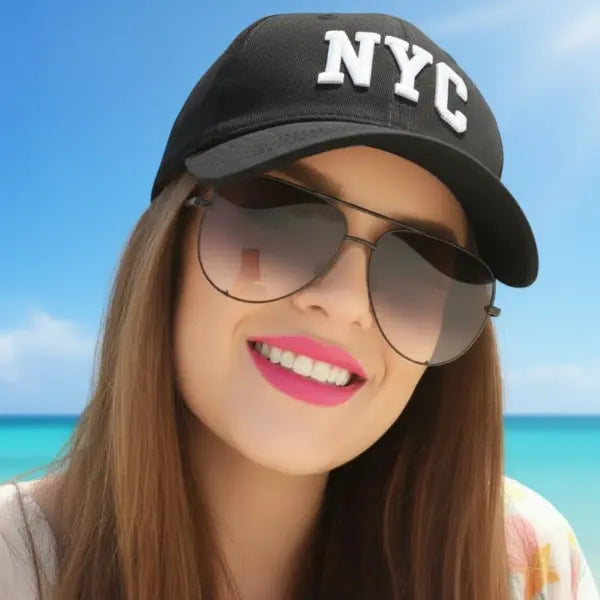 Woman wearing an NYC cap and Envy sunglasses with a beach background