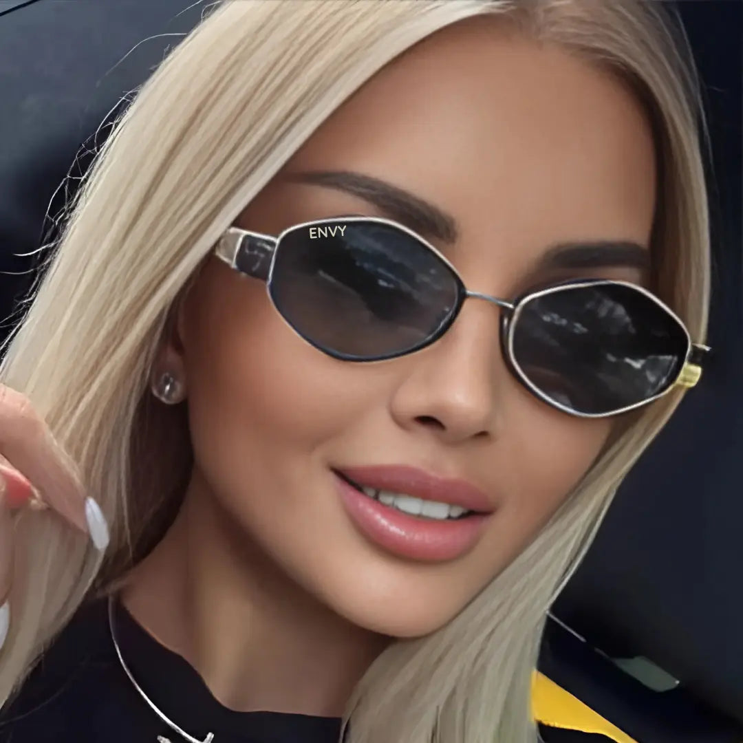 A close-up of a blonde woman wearing Envy brand cat-eye sunglasses with dark lenses and silver metal frames.