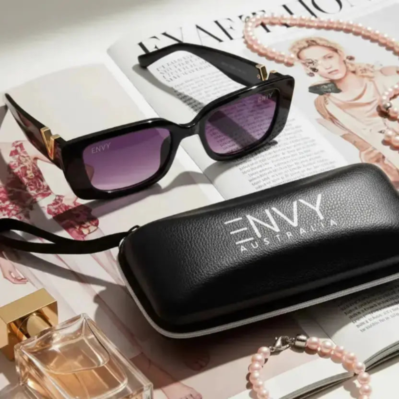 Black sunglasses with purple lenses on a magazine next to an 'Envy Australia' case.