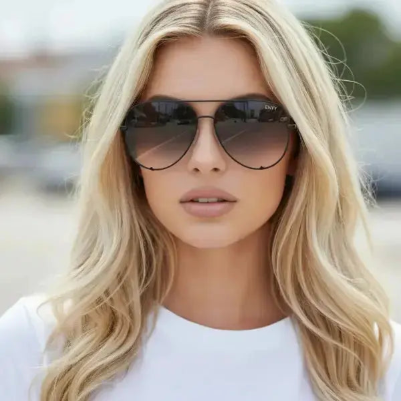 Woman wearing Envy Ombre Pilot Black sunglasses with a blurred outdoor background
