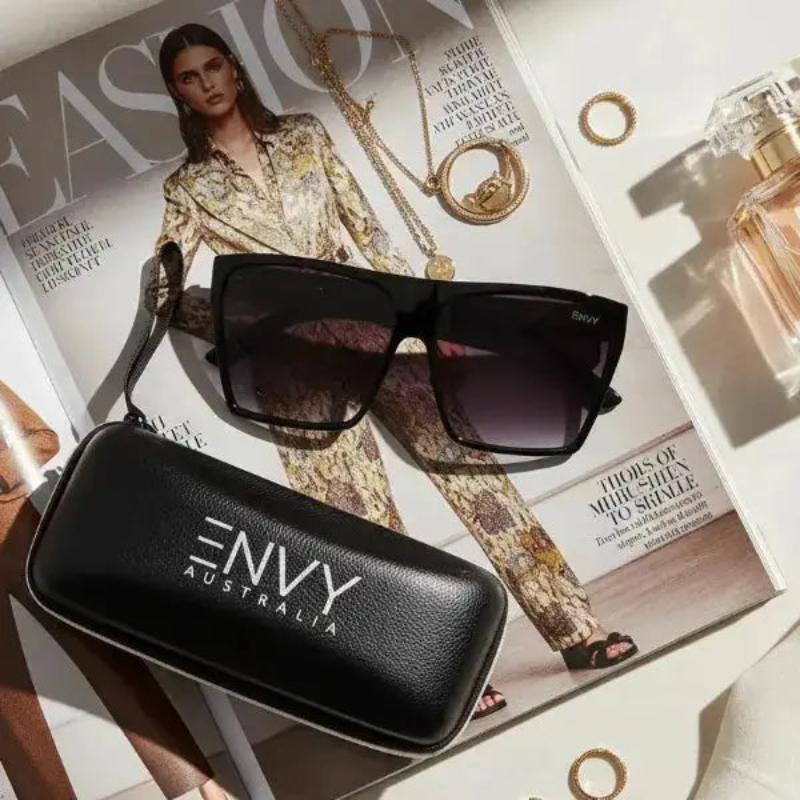 Sachi Black sunglasses with 'ENVY Australia' case on a fashion magazine