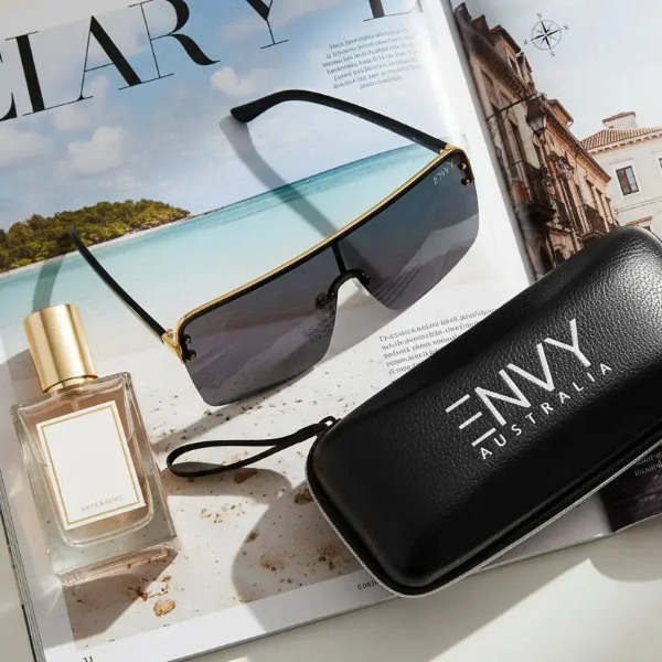 Sunglasses, perfume bottle, and 'Envy Australia' case on a magazine