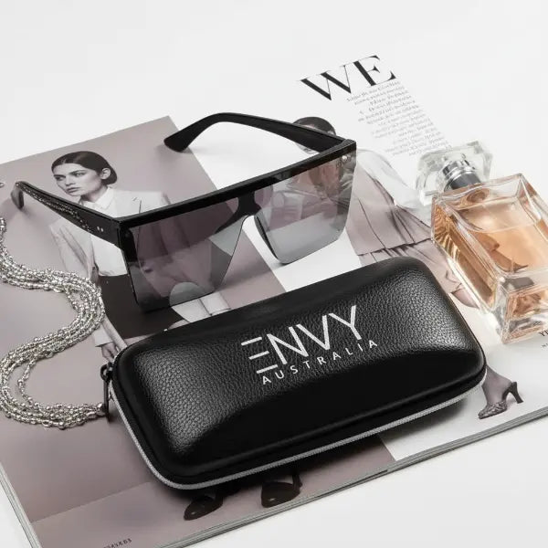Black sunglasses with 'Envy Australia' case and perfume bottle on magazine