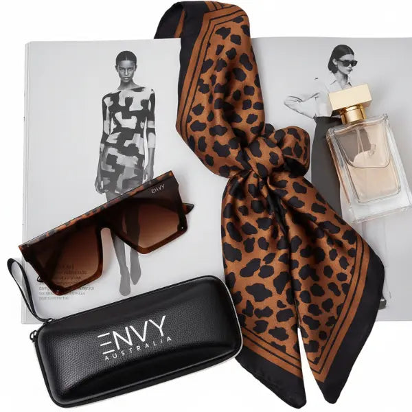 Leopard print scarf, Envy sunglasses with case, and perfume bottle on a white background