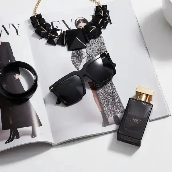 Black Envy sunglasses, necklace, and perfume bottle on a magazine