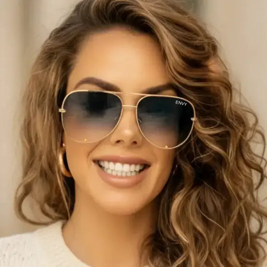 Woman wearing golden black fade framed sunglasses with a blurred background