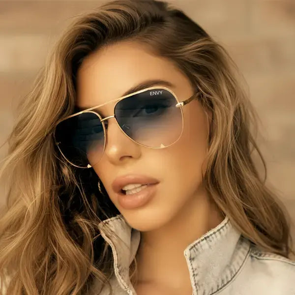 Woman wearing gold black fade sunglasses with a blurred background