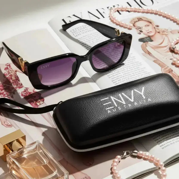 Black sunglasses with purple lenses on a magazine next to an 'Envy Australia' case.