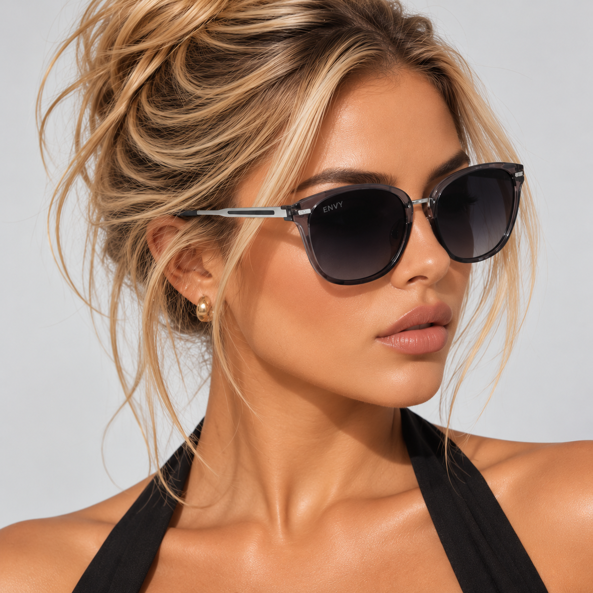 A close-up of a woman wearing cat-eye sunglasses with dark lenses and silver-toned metal frames. The brand name 'ENVI' is visible on the temple arm.